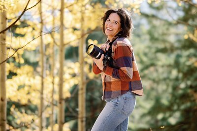 Colorado Elopement Photographer smiles with her camera during fall Colorado wedding.