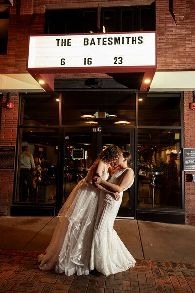 Two brides kissing in front of a marquee.