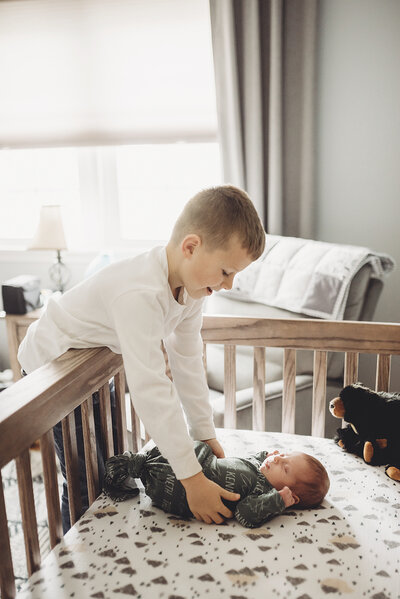Boy putting newborn baby in a crib in nursery in Washington DC