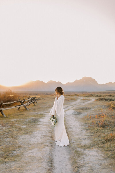 Bride stands in front of majestic Teton Mountains in Jackson Hole Wyoming photographed by Jackson Hole luxury destination film wedding photographer Magnolia Tree Photo Company