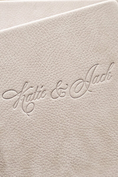 Close-up of white textured leather with Katie & Jack embossed in elegant cursive script.