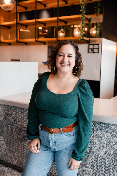 woman smiling and leaning up against a colorful counter