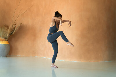 In a desert landscape, Sarah showcases a graceful Natarajasana or Dancer's Pose, reflecting focus and the art of creative yoga sequencing.