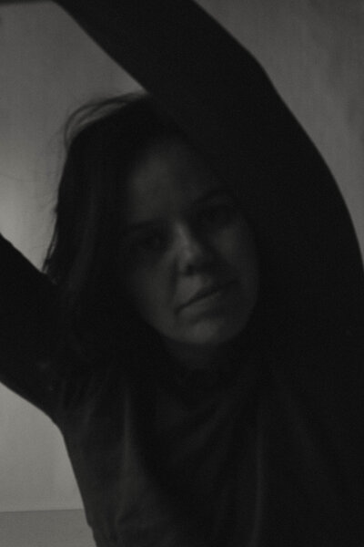 Black and white portrait, gazing into the camera with arms raised, for an expressive and artistic self-portrait.