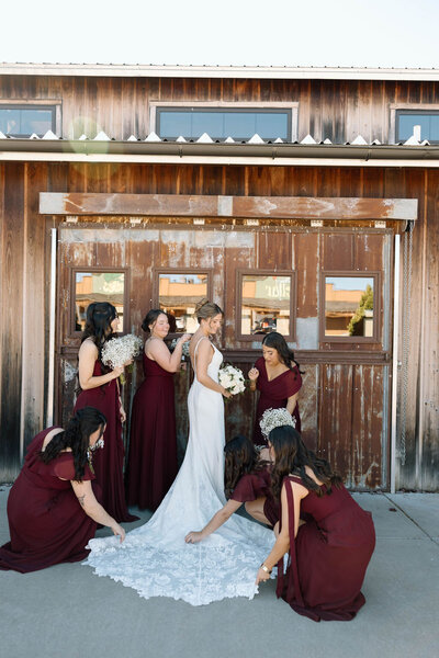 Bride surrounded by bridesmaids adjusting her dress