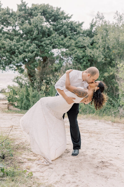 Couple kisses during sunset on a beach on their wedding day.