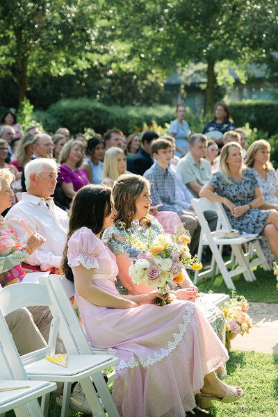 Austin wedding photo of ceremony guests with woman holding colorful bouquet captured in candid documentary style by Austin Wedding Photographer, Erin Marcin.
