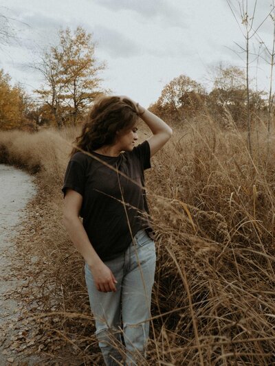 Woman standing in a field with a moody, atmospheric vibe
