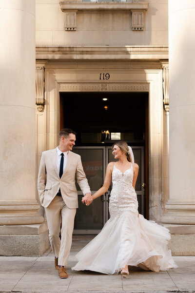candid photo of a bride and groom walking and laughing on Sparks Street taken by Ottawa wedding photographer JEMMAN Photography
