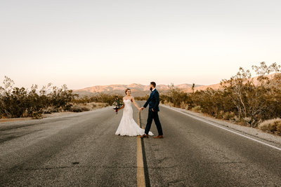 a couple walking along the road in Joshua Tree on  their elopement day