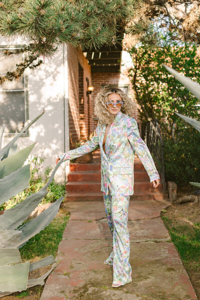 She owns the walkway in this floral pantsuit — a confident fashion portrait framed by mid-century brick and lush greenery. Greenville SC, Dani Lacey.