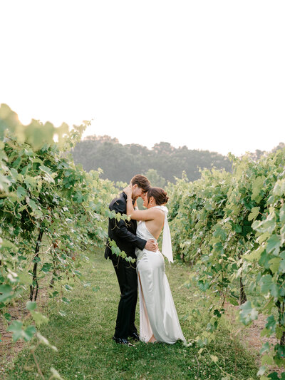 Bride and groom embracing in a green vineyard during golden hour for their destination wedding in Minnesota.
