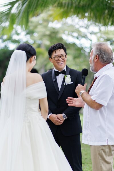 A couple standing up during their wedding ceremony laughing together 