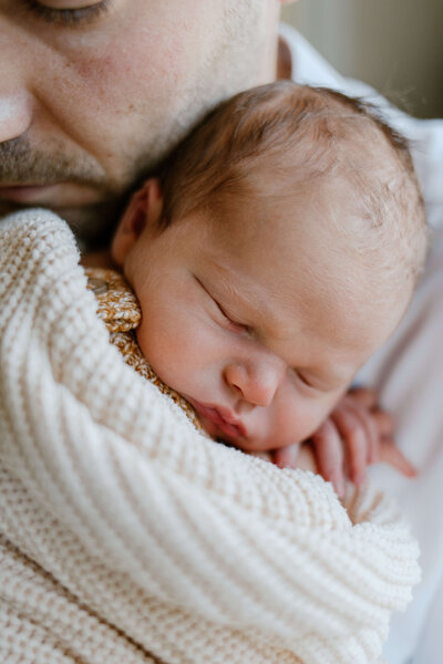 Close up image of a dad holding a newborn baby