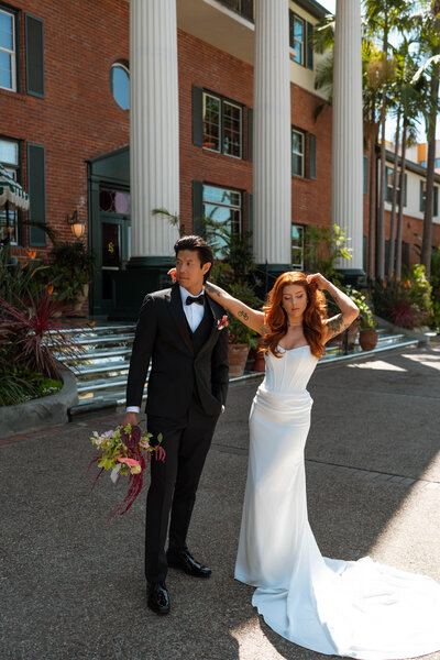 a bride and groom posing in front of a hotel 