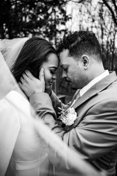 Black and white shot of Yana and Brian behind her veil during bridal portraits after their wedding ceremony at Kincaid Manor, capturing their intimate moment.
