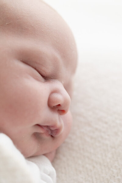 Puur en minimalistisch: een newborn shoot aan huis waarbij de baby centraal staat op een creme achtergrond.