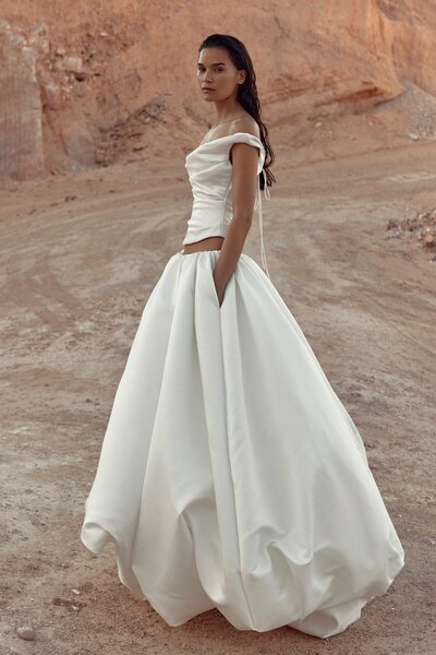 KYHA BRIDE 'Evans' stocked at Sunday's Bride London, UK. Embrace your inner whimsy in the cloud-like KYHA BRIDE Opal skirt. A feat in construction, this sculptural masterpiece is adjustable in length, giving you the option to take Opal from floor length opulence, to playful knee length, to even a powder puff strapless dress. Cut from duchess satin, Opal takes this season's most sought-after on-and-beyond the runway silhouette to new couture level.