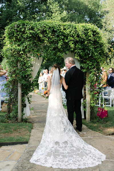 The bride walks down the aisle with her father during an outdoor ceremony at Hummingbird House in Austin, Texas. Photographed by Austin wedding photographer, Erin Marcin Photography.
