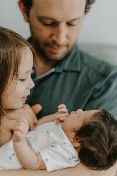 Newborn Photographer, couple looking at newborn baby lying on bed