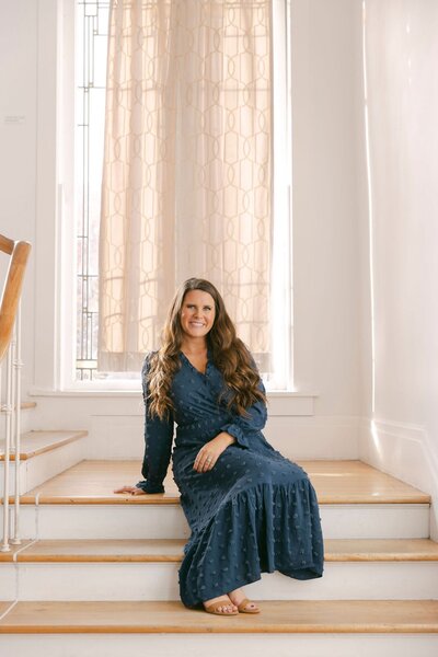 Jennifer sitting on the top of an elegant staircase smiling