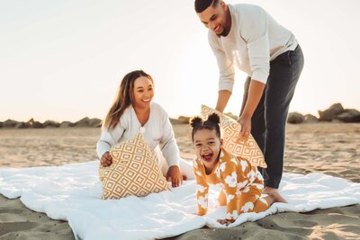family sitting on a blanket on the beach