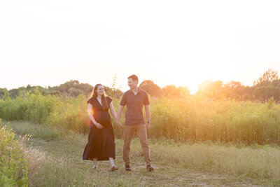 A maternity and newborn photographer photographs an expecting couple at sunset. 
