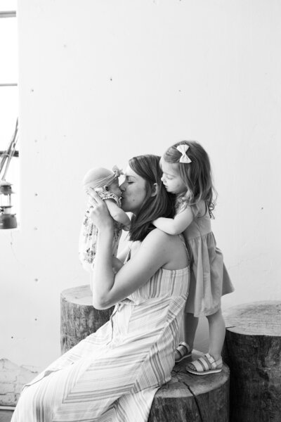 Mother kissing baby with toddler nearby
