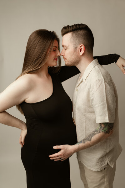 Expecting parents holding each other while embracing baby bump during a studio maternity session in Maple Grove, Minnesota
