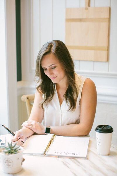 woman sitting at a desk writing in a planner