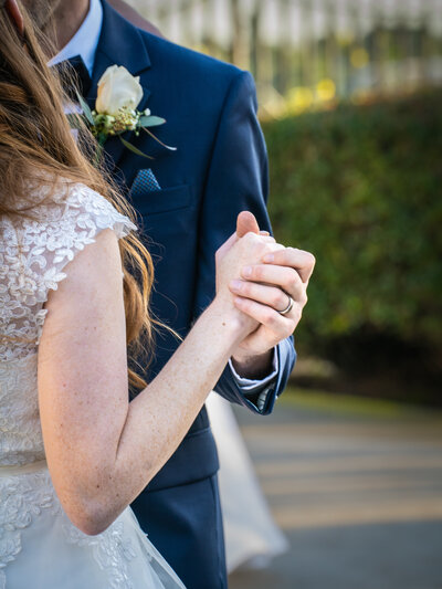 Grooms ring and boutonniere stand out in this frame, which features a bride and groom's hands during their first dance. Photo by SAVI Photographer - San Diego California Photographer