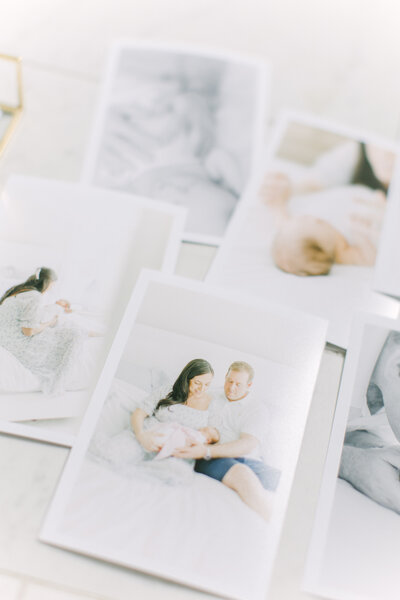 A flatlay image of printed photos of a newborn session