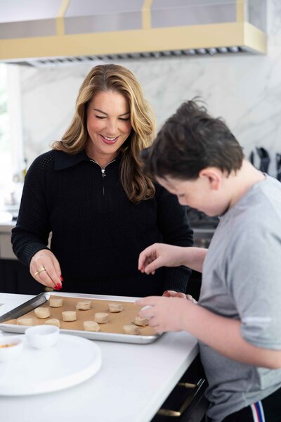 woman with dark hair in black sweater cooking with son in grey shirt