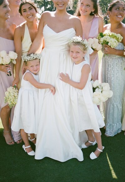 Flower girls hugging bride.