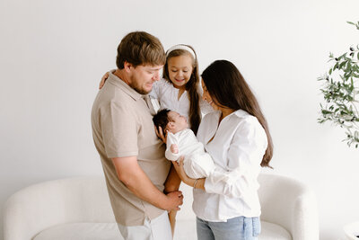 Parents and big sister smiling at newborn baby during photo session with Indianapolis newborn and family photographer Capturing Simplicity Photography