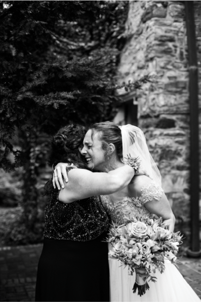 Bride in a wedding gown hugging mom on her wedding day.