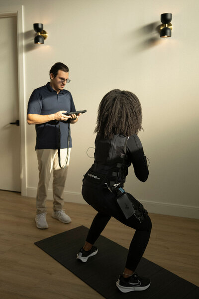 Trainer coaching a client during an EMS training session, demonstrating personalized fitness in action