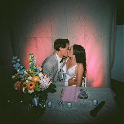 couple kissing on film in front of colorful flowers