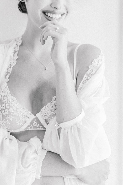 black and white, bride smiling past the camera in her lingerie