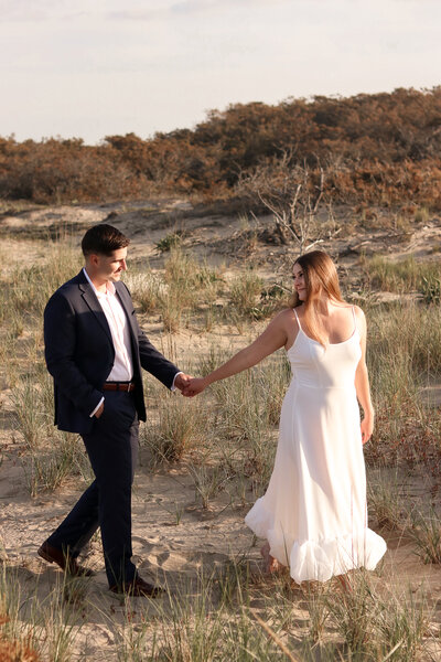 engagement photography of couple on cape cod beach holding hands in dunes