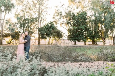 Engaged couple embrace as they pose for engagement photos at the Huntington Beach Central Park