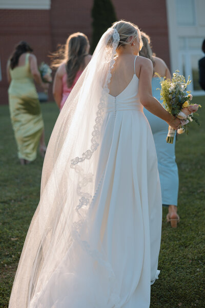 Bride walks up a hill while holding colorful bouquet of flowers