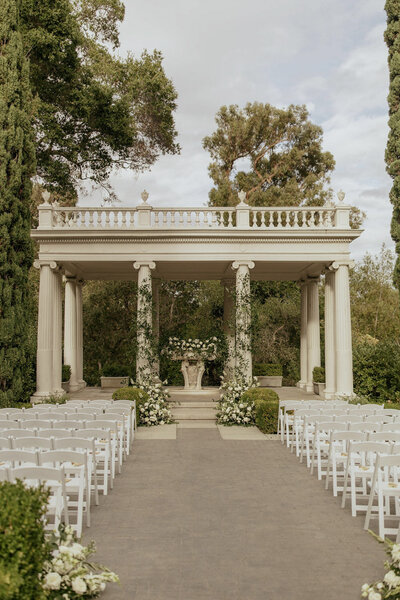 Ceremony space with white chairs and floral altar backdrop