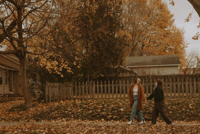 A couple holds hands while walking down the sidewalk, laughing and having fun