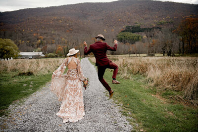 A bride and groom traveling down a mountain path after their wedding. The groom is jumping energetically.