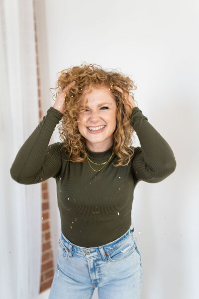Red headed woman plays with her hair and smiles into the camera
