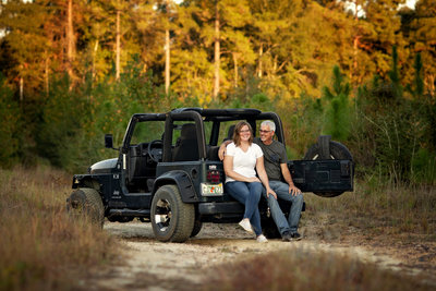 Couple sitting together in the back of their jeep.