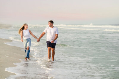 A couple holding hands while walking through the ocean in Stone, Harbor New Jersey
