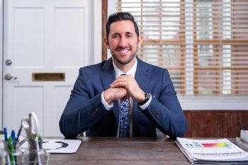 Dr. Antonio Reale, ND, MS, standing in a medical office, smiling confidently at the camera