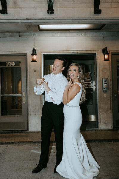 bride and groom showing their rings outside of their venue with trendy flash photography
